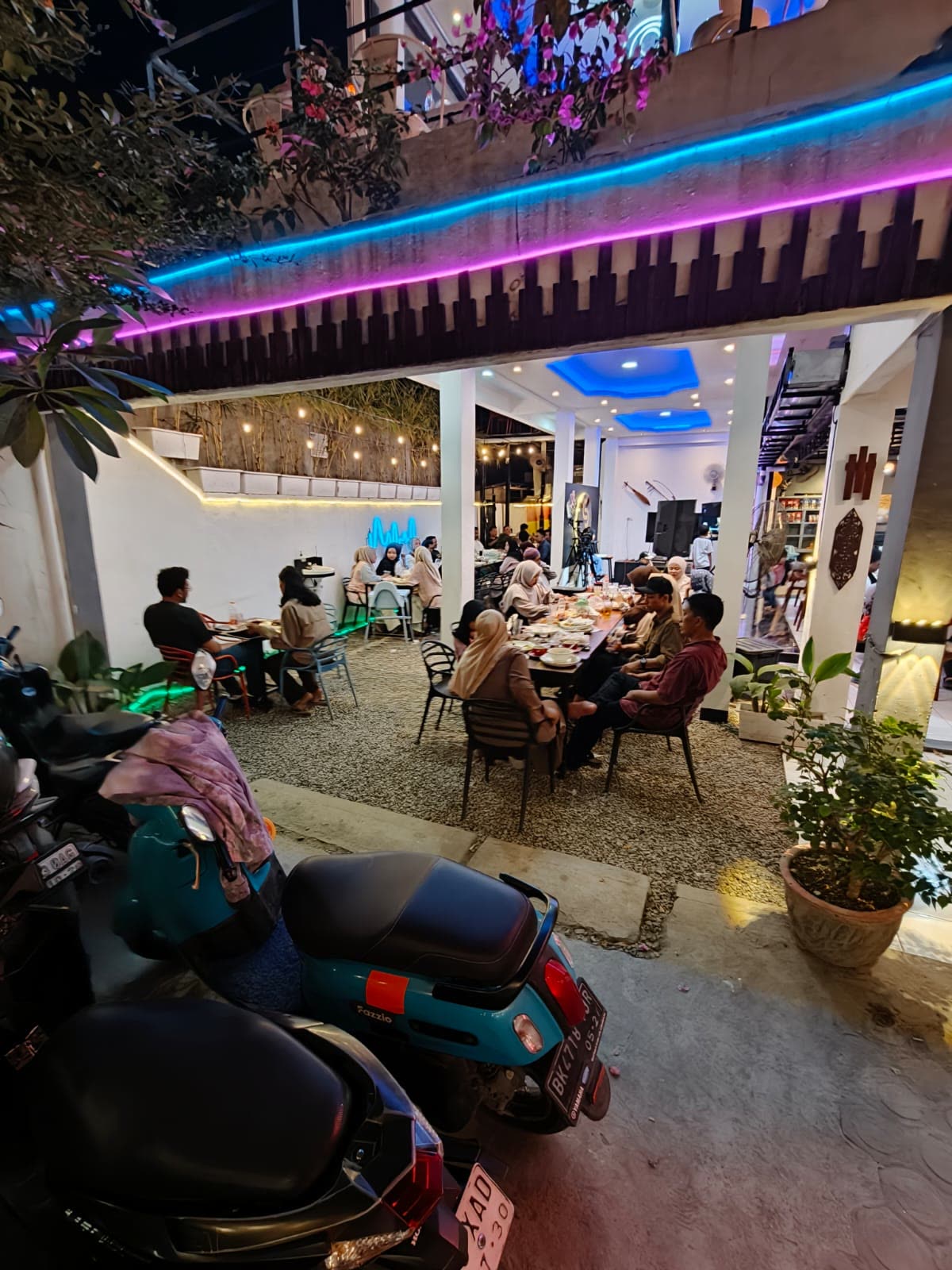 Area outdoor lounge Sam's Coffee & Eatery dengan lampu neon